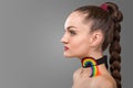 Portrait of brunette woman with long pigtail. decoration on the neck in the form of a rainbow over grey background