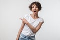 Portrait of brunette woman with short hair in basic t-shirt rejoicing and pointing finger at copyspace Royalty Free Stock Photo