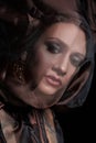 Portrait of a brunette woman through a transparent dark fabric. Beauty and makeup girl. There is no focus