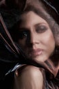 Portrait of a brunette woman through a transparent dark fabric. Beauty and makeup girl. There is no focus