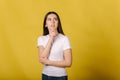 Portrait of brunette woman on yellow background in studio. Female thinking. place for text