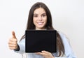 Portrait of brunette young smiling woman holding a tablet with blank screen showing thumb up and looking at camera isolated on Royalty Free Stock Photo