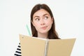 Portrait of brunette young woman, creative girl thinking, holding pen and notebook, making notes, writing in her diary Royalty Free Stock Photo