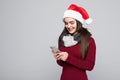 Portrait of a brunette young woman in red santa claus using mobile phone isolated on the gray background Royalty Free Stock Photo