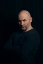 Portrait of a brutal bald man in a dark style on a black background. a guy in a black turtleneck boldly looks at the Royalty Free Stock Photo