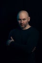 Portrait of a brutal bald man in a dark style on a black background. a guy in a black turtleneck boldly looks at the Royalty Free Stock Photo