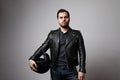 Portrait of a brutal bearded biker man holding helmet dressed in a black leather jacket. Free space for text. Royalty Free Stock Photo