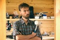 Portrait of brutal bearded worker man in his carpenter workshop, different construction tools in the background. DIY concept