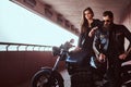 Portrait of a brutal fashionable biker dressed in a black leather jacket with sunglasses sitting on his custom-made Royalty Free Stock Photo