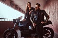 Portrait of a brutal fashionable biker dressed in a black leather jacket with sunglasses sitting on his custom-made Royalty Free Stock Photo