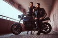 Portrait of a brutal fashionable biker dressed in a black leather jacket with sunglasses sitting on his custom-made Royalty Free Stock Photo