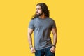 Portrait of brutal handsome bearded young man model with long curly hair in grey tshirt standing and looking away with serious Royalty Free Stock Photo