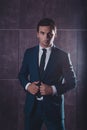 Portrait of brutal handsome man in black suit holding hands on suit Royalty Free Stock Photo