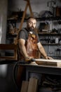 Portrait of a brutal master carpenter in an apron in workshop