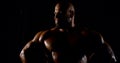 Portrait of a brutal muscular bald bearded male bodybuilder close-up on a black background, he poses