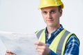 Studio Portrait Of Builder Architect Looking At Plans Against White Background