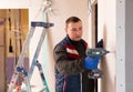 Portrait of builder handyman working with electric drill in repairable room Royalty Free Stock Photo