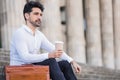 Portrait of business drinking coffee on stairs outdoors.