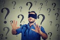 Portrait business man blindfolded stretching his arms out walking through many questions