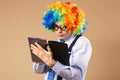 Portrait of business man in clown wig using a tablet to access t Royalty Free Stock Photo