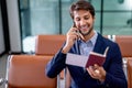 Portrait of business man hold passport and boarding pass also use mobile phone to contact with his friend during wait to the