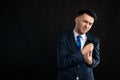 Portrait of business man wearing blue business suit and tie with his hand on his chest suffering from acute pain