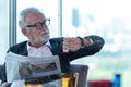 Portrait business partner executive smart man sitting and reading newspaper in restaurant. Old people businessman see the time and Royalty Free Stock Photo