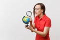 Portrait of business teacher woman in red shirt holding and looking through magnifying glass on globe on white