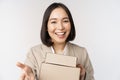 Portrait of business woman, asian saleswoman pointing at you, giving boxes with orders, standing in suit over white Royalty Free Stock Photo