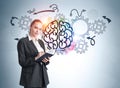 Portrait of business woman in formal wear standing in front of light blue wall with colorful brain sketch with gear wheels, taking Royalty Free Stock Photo
