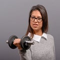 Portrait of business woman lifting weights against gray background Royalty Free Stock Photo