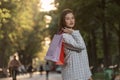 Portrait of business woman with shopping bag in hands on park background. Beautiful young girl in jacket with purchases Royalty Free Stock Photo