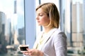 Portrait of business woman standing with coffee near window. Downtown area background. Royalty Free Stock Photo