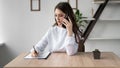 Portrait of a business woman working from home sitting at a desk talking or talking on the phone with a client and Royalty Free Stock Photo