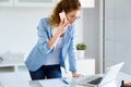 Business young woman talking on the mobile phone while using her laptop in the office. Royalty Free Stock Photo