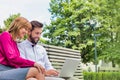 Portrait of businessman and businesswoman sitting on bench while working on laptop Royalty Free Stock Photo