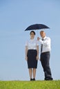 Portrait of businessman and businesswoman under umbrella in park Royalty Free Stock Photo