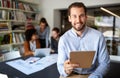 Portrait of businessman holding tablet in office and colleagues discussing in background Royalty Free Stock Photo