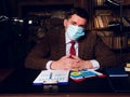 Portrait of a businessman in medical mask sitting at the table. Royalty Free Stock Photo