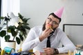 portrait of businessman in party cone eating birthday cupcake Royalty Free Stock Photo