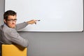 Portrait of businessman pointing at whiteboard and making face in office Royalty Free Stock Photo