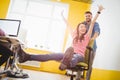 Portrait of businessman pushing cheerful colleague sitting in chair at creative office Royalty Free Stock Photo