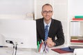 Portrait: Businessman sitting in his office with suit and tie.