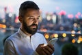 A businessman with smartphone at sunset, text messaging.