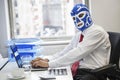 Portrait of businessman using laptop while wearing wrestling mask at office desk Royalty Free Stock Photo