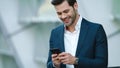 Portrait businessman using smartphone. Man smiling with phone in hand outdoors Royalty Free Stock Photo