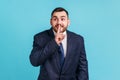 Portrait of businessman wearing official style suit holding finger near lips showing shh gesture Royalty Free Stock Photo