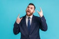 Portrait of businessman wearing official style suit showing rock and roll sign hand gesture, screaming, having excited facial