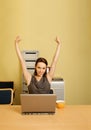 Portrait of businesswoman with arms raised, cup and laptop on desk Royalty Free Stock Photo