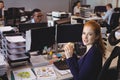 Portrait of businesswoman having snack while colleagues working in creative office Royalty Free Stock Photo